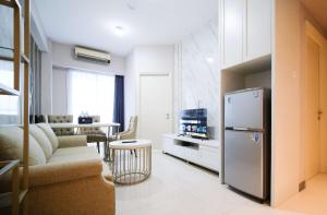 a kitchen with a refrigerator and a living room at Luxury and Clean 2BR at Benson Supermall Mansion Apartment By Travelio in Surabaya