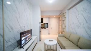 a living room with a couch and a tv at Luxury and Clean 2BR at Benson Supermall Mansion Apartment By Travelio in Surabaya
