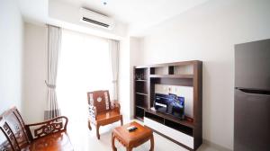 a living room with a television and a table and chairs at Simple and Clean 2BR at Grand Sungkono Lagoon Apartment By Travelio in Surabaya