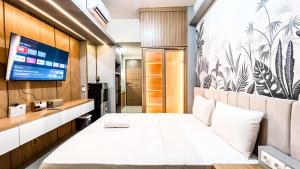 a bedroom with a white bed and a tv at Comfort Studio Apartment Vida View Makassar By Travelio in Pampang +16 photos