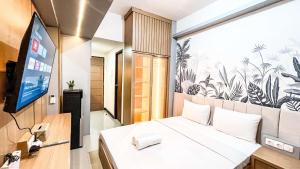 a room with a bed and a flat screen tv at Comfort Studio Apartment Vida View Makassar By Travelio in Pampang