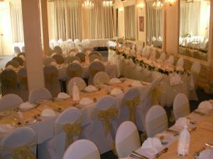 un salón de banquetes con mesas blancas y sillas blancas en The Hydro Hotel, en Douglas