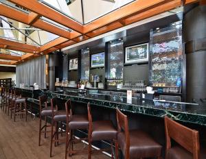 a bar in a restaurant with brown chairs at Ramada by Wyndham Buffalo Downtown in Buffalo
