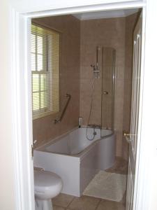 a bathroom with a bath tub and a toilet at The Hall Farm Bed And Breakfast in Tilbrook