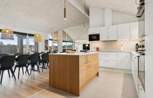 a kitchen and dining room with white cabinets and black chairs at Stunning Home In Ålbæk With Sauna in Ålbæk +22 photos