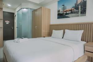 a bedroom with a large white bed and a glass door at Modern Studio at Pacific Garden - Campus Town @Alam Sutera Apartment By Travelio in Tangerang +19 photos
