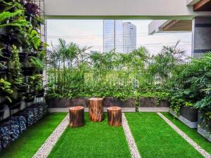 a small garden with two logs and grass at Modern Studio at Pacific Garden - Campus Town @Alam Sutera Apartment By Travelio in Tangerang