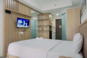 a bedroom with a white bed and a flat screen tv at Modern Studio at Pacific Garden - Campus Town @Alam Sutera Apartment By Travelio in Tangerang
