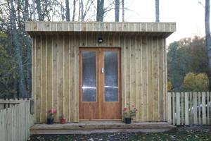 un pequeño cobertizo de madera con puerta de madera en BCC Lochness Glamping, en Bearnock
