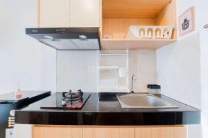 a small kitchen with a sink and a stove at Minimalist and Strategic Studio at Serpong Garden Apartment By Travelio in Tangerang