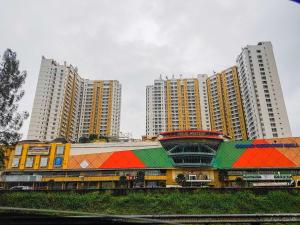 a building with a colorful roof in front of tall buildings at Cozy and Minimalist Studio Great Western Apartment By Travelio in Tangerang