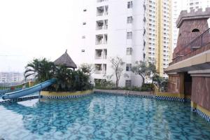 a large swimming pool with a blue slide in front of a building at Cozy and Minimalist Studio Great Western Apartment By Travelio in Tangerang