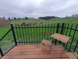 a bench sitting on a deck with a fence at Black Horse Cabin 2 by Tiny Away in Parakakau +16 photos