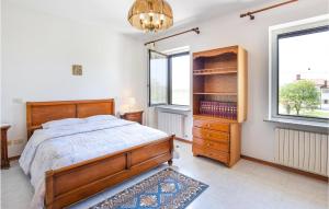 a bedroom with a bed and a dresser and two windows at 2 Bedroom Cozy Apartment In Grado in Grado