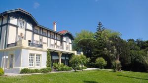 a large white house with a lawn in front of it at Las Carolinas Garden in Santander
