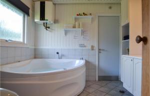 a large white tub in a bathroom with a window at Amazing Home In Hvide Sande With Sauna in Bjerregård