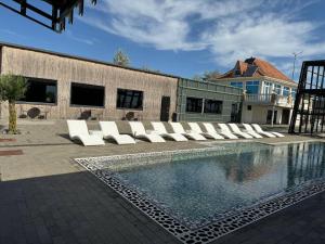 a pool with white lounge chairs next to a building at Black Sea Resort in Primorskoye