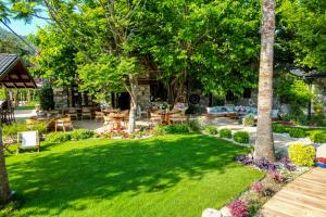 a green yard with a table and chairs and trees at Kaya Villas Exclusive in Kayakoy