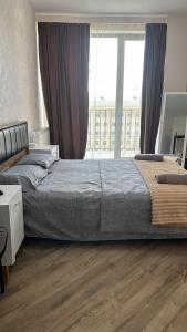 a bedroom with a bed and a large window at Wine Garden Apartment in Tbilisi City
