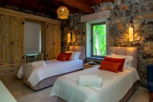 two beds in a room with a stone wall at Kaya Villas Exclusive in Kayakoy