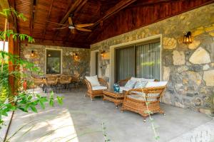 a patio with wicker furniture and a stone wall at Kaya Villas Exclusive in Kayakoy