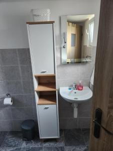 un baño con lavabo y espejo en Melanie apartman 2, en Veľký Meder 7 fotos más