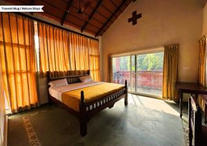 a bedroom with a bed and a large window at Pepper Corn Retreat By Travent Mug in Sakleshpur