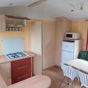 eine kleine Küche mit Herd und Mikrowelle in der Unterkunft Mobilheim für 5 Personen ca 29 m in Baarland, Zeeland Küste von Zeeland in Baarland