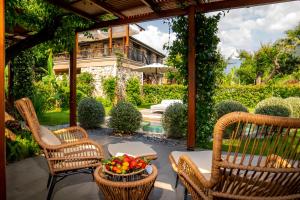 a patio with two chairs and a table with a bowl of fruit at Kaya Villas Exclusive in Kayakoy