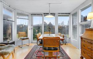 a dining room with a table and chairs and windows at Holiday Home Ydunvej Ebeltoft in Ebeltoft