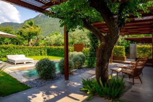 a patio with a tree and chairs and a pool at Kaya Villas Exclusive in Kayakoy