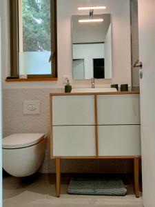 een badkamer met een wastafel, een toilet en een spiegel bij La villa des vignes in Castillon-du-Gard