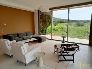 een woonkamer met witte meubels en een groot raam bij La villa des vignes in Castillon-du-Gard