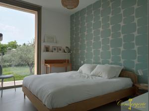 een slaapkamer met een bed met een groene muur bij La villa des vignes in Castillon-du-Gard