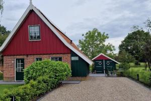 a red and green barn with a garage at Huisje Weidezicht in Lievelde