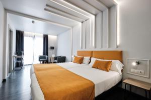 1 dormitorio con 1 cama blanca grande con manta naranja en Hotel Lux Santiago, en Santiago de Compostela