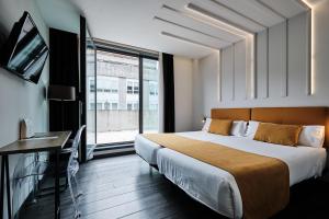 Un dormitorio con una cama grande y una ventana grande. en Hotel Lux Santiago, en Santiago de Compostela