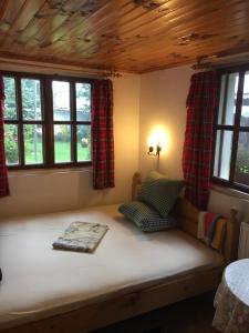 a bed in a room with two windows at Dyadovata Kashta in Elena
