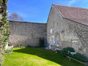an old stone building with a grass yard next to it at Le presbytère 30 min de Beauval in Les Montils