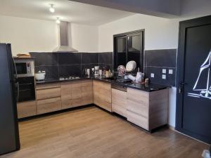 eine Küche mit schwarzen und braunen Schränken und einer Theke in der Unterkunft La maison du bonheur in Le Lambert