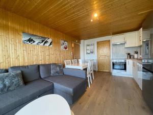 a living room with a couch and a table and a kitchen at Homency - Résidence les Chanses E3 in L'Alpe-d'Huez