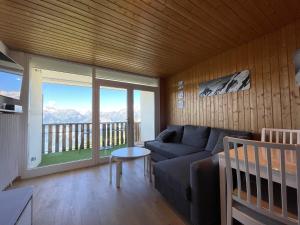 a living room with a couch and a large window at Homency - Résidence les Chanses E3 in L'Alpe-d'Huez