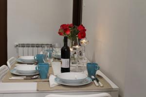 uma mesa com pratos e uma garrafa de vinho e rosas vermelhas em Vatican Santamaura 39 em Roma