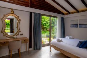 a bedroom with a bed and a desk and a mirror at Kaya Villas Exclusive in Kayakoy