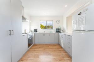 a white kitchen with white cabinets and a window at Just Beachy in Island Beach