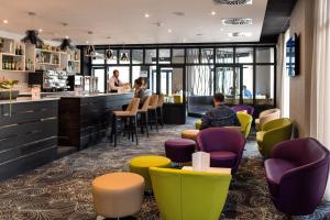 a restaurant with colorful chairs and a bar at Mercure Cherbourg Centre Port in Cherbourg en Cotentin