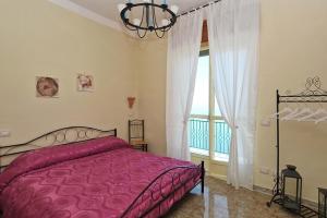 a bedroom with a pink bed and a window at La Rosa dei Venti in Furore