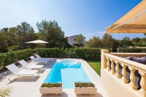 a swimming pool on a patio with chairs and an umbrella at Villa Pasero Platon - 300 Meter vom Strand Cala Anguila entfernt in Porto Cristo