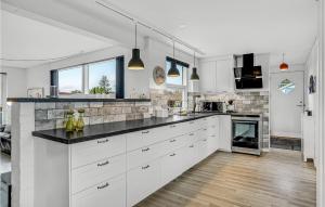 una cucina con armadietti bianchi e ripiani neri di 3 Bedroom Nice Home In Nordborg a Nordborg