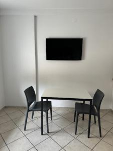 a table with two chairs and a television on a wall at Cozy flat near Tivoli park with free parking in Ljubljana